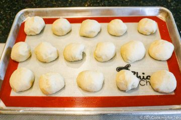 Balls of raw dough on a baking tray with a mat