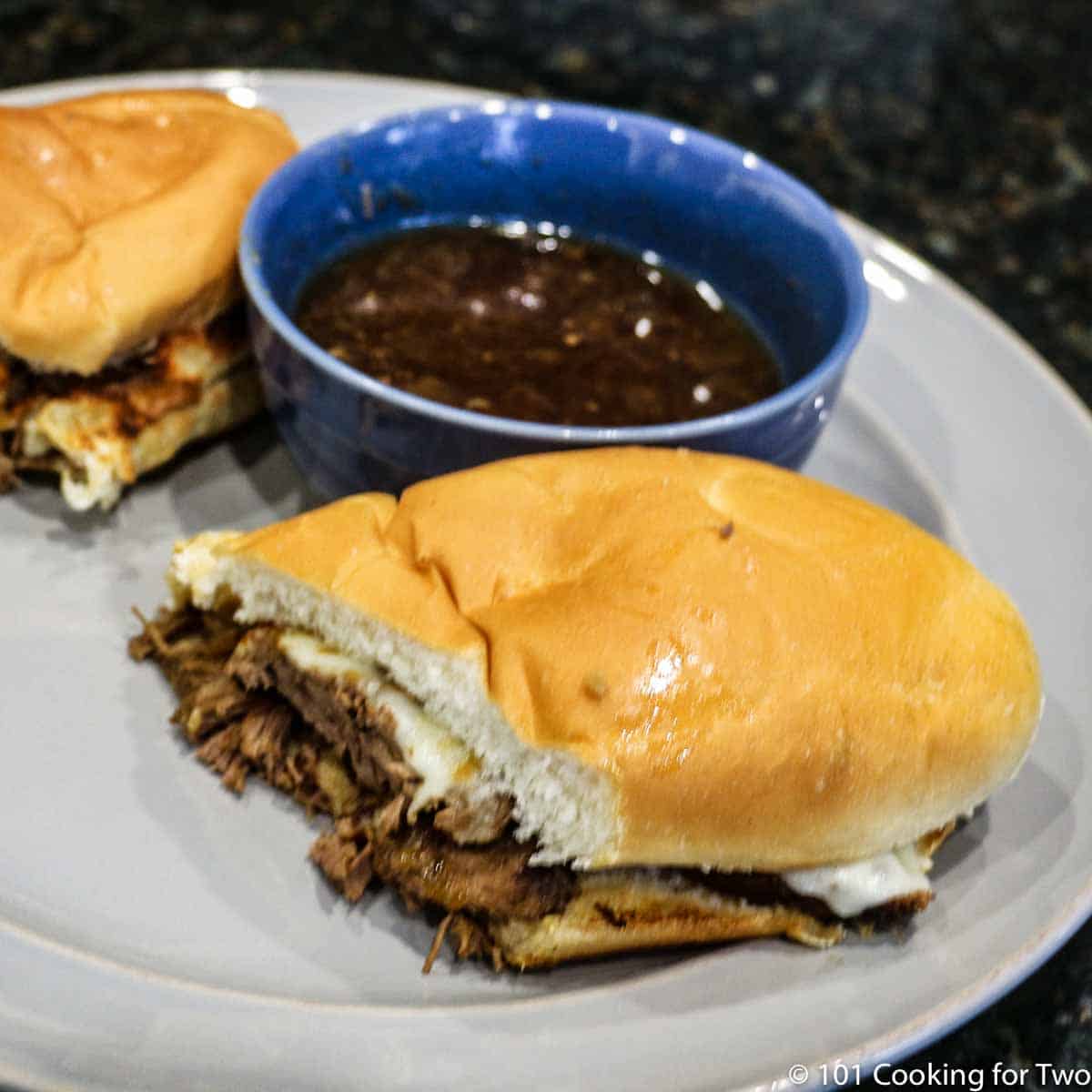 French dip sandwich with dip on gray plate