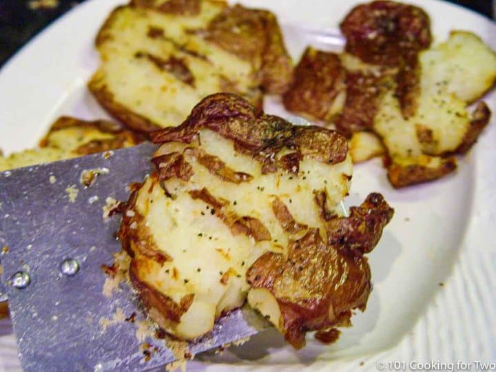 Moving smashed potatoes to a plate with a spatula