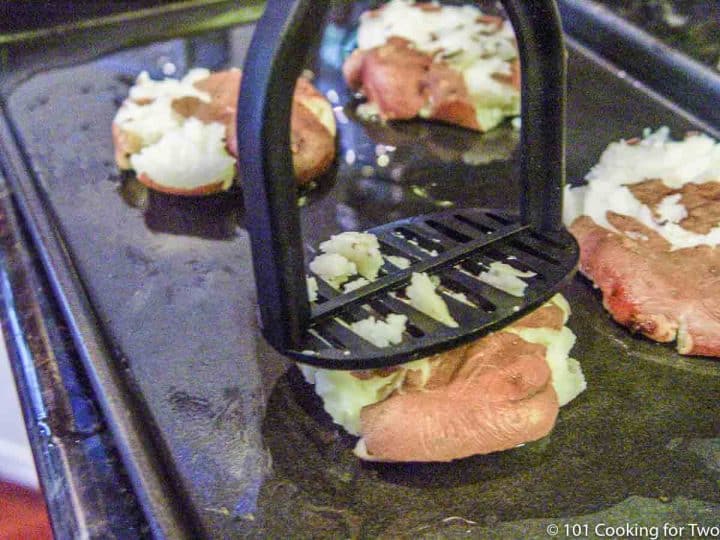 Smashing red potatoes with a potato masher