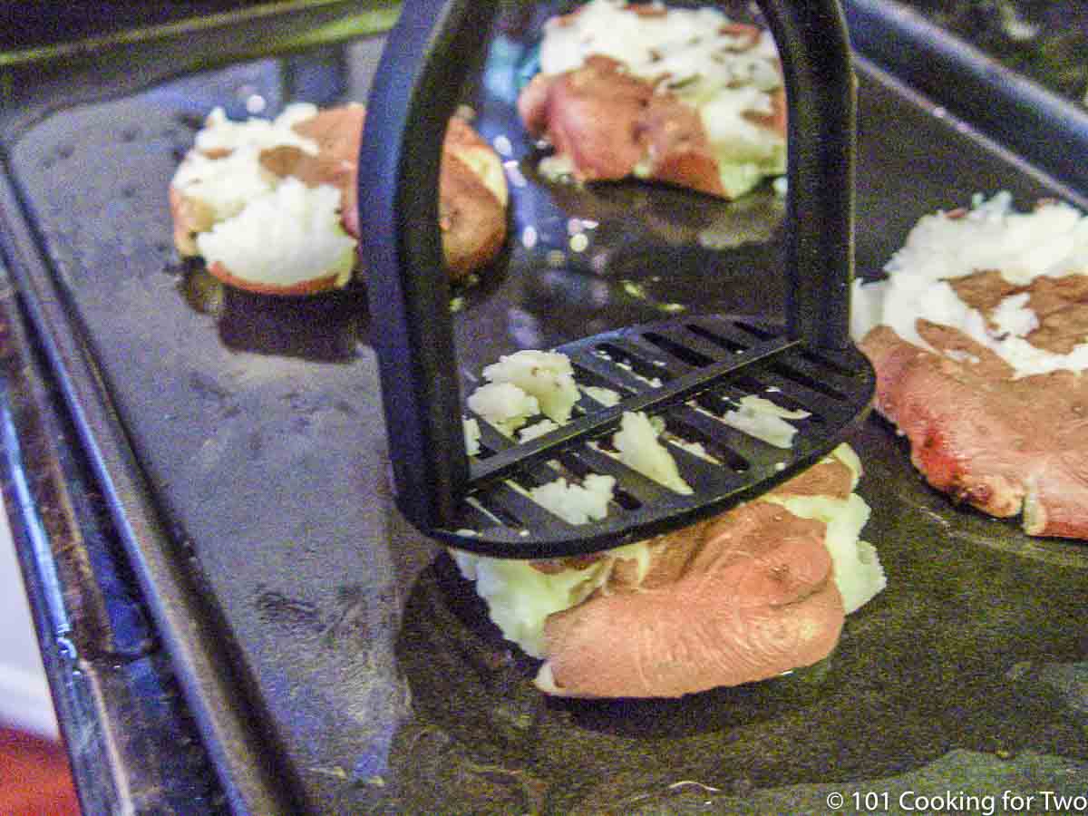 Smashing red potatoes with a potato masher.