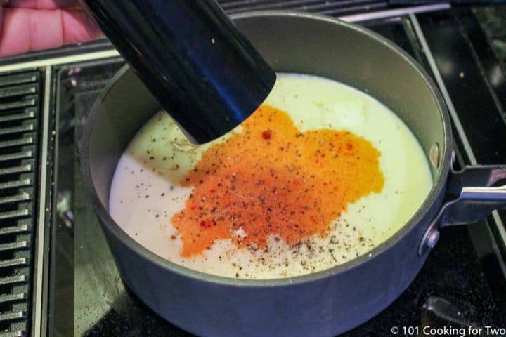 adding pepper to black pan with other ingredients