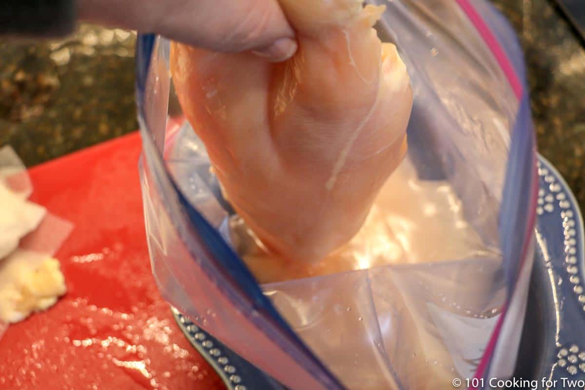 adding raw chicken to a bag to brine