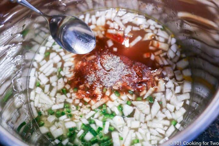adding spices to the chopped onion and broth in hte cooker