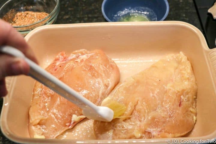 brushing chicken in the baking dish with butter
