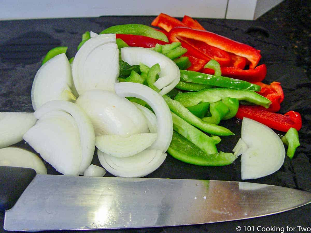 chopped onion with red and green pepper on a black board.