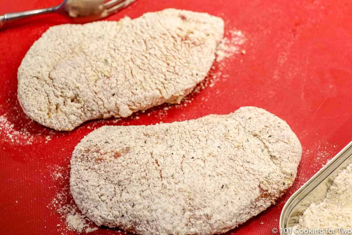 coated pork chops setting on a red mat