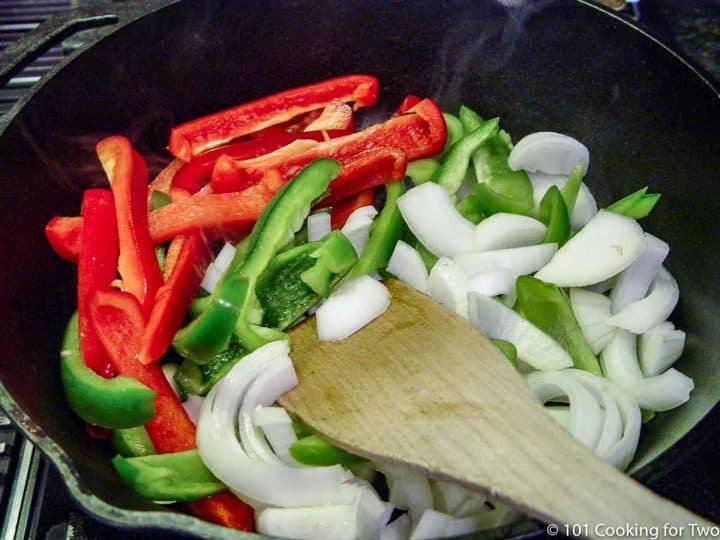 cooking peppers and onions in a cast iron skillet