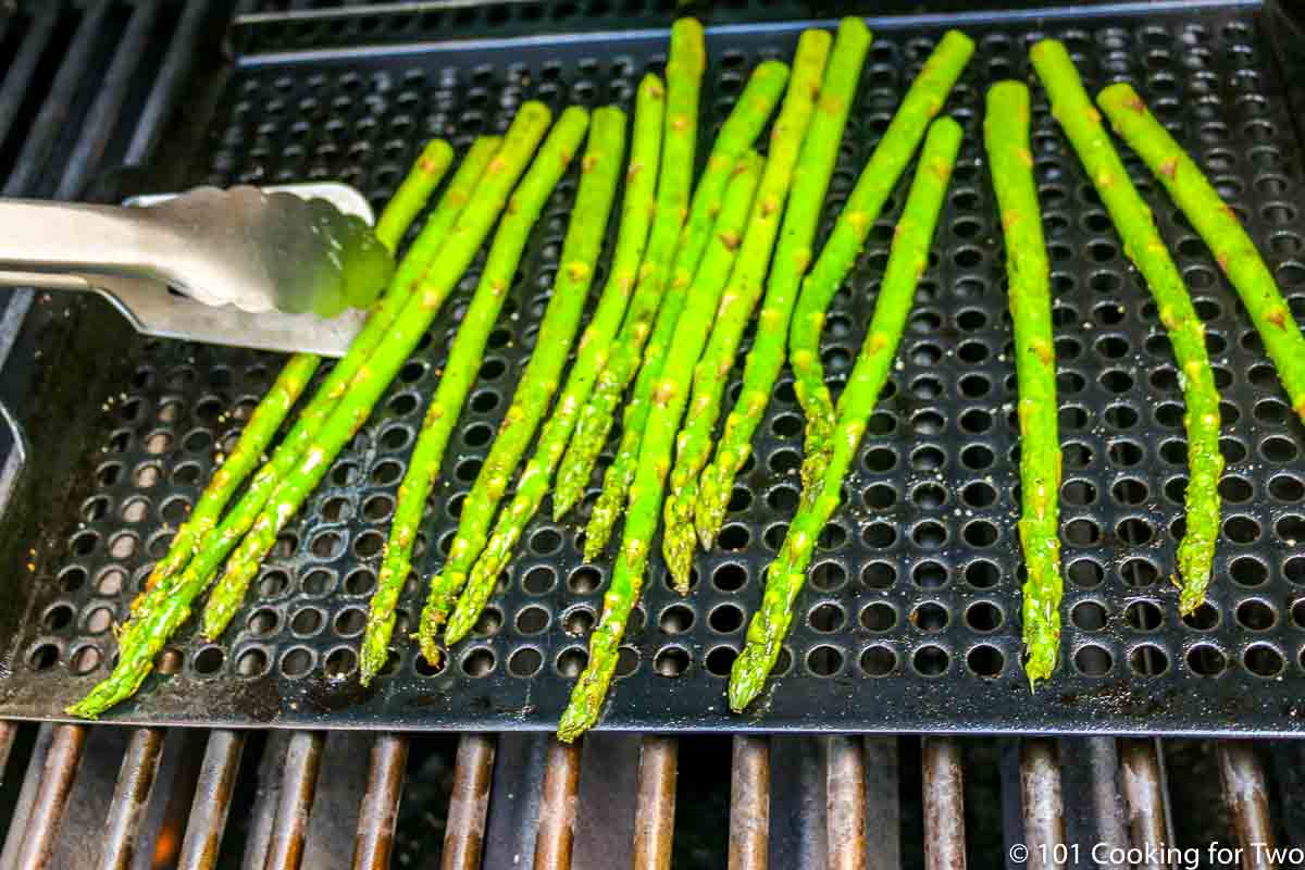 flipping the asparagus on the grill pan.