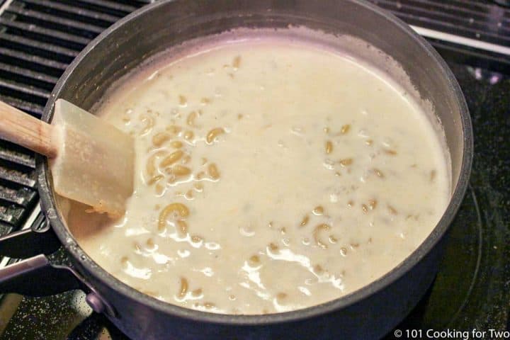 mixing pasta into the pan with milk and spices