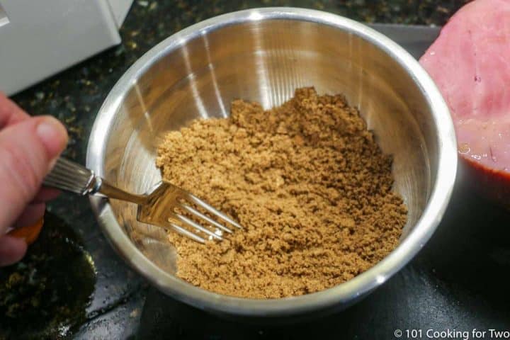 mixing spices with brown sugar in a metal bowl