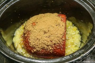 placing the coated ham on the pineapple in the crock pot