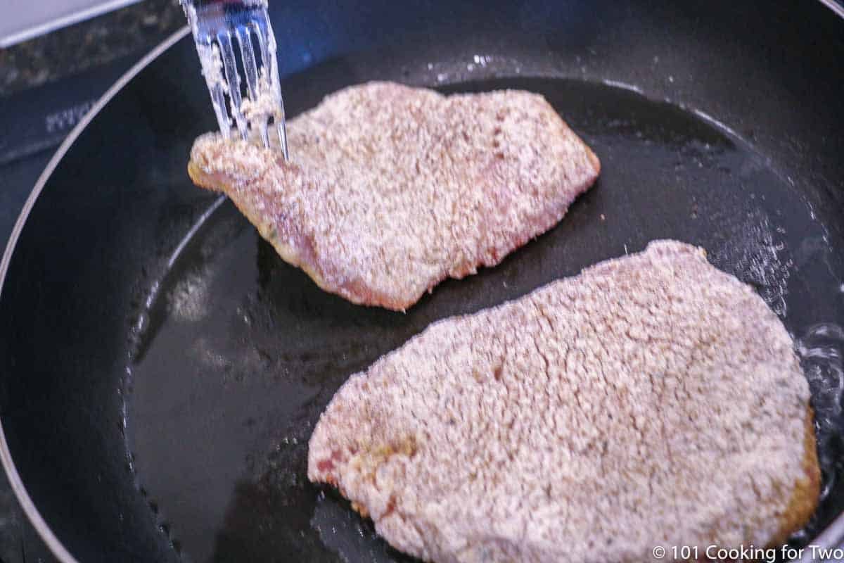 placing the coated pork chop in the pan with oil