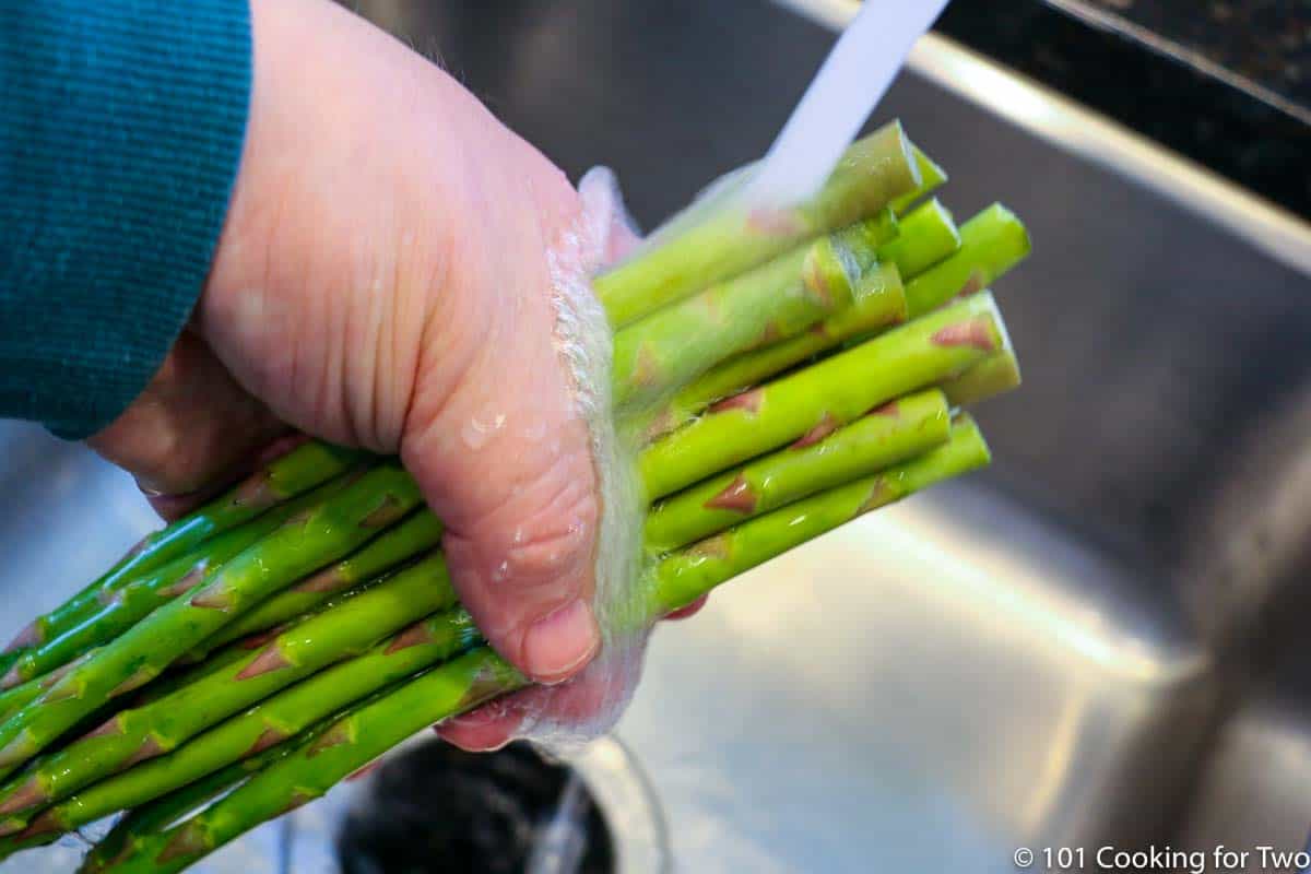 rinsing asparagus under running water.