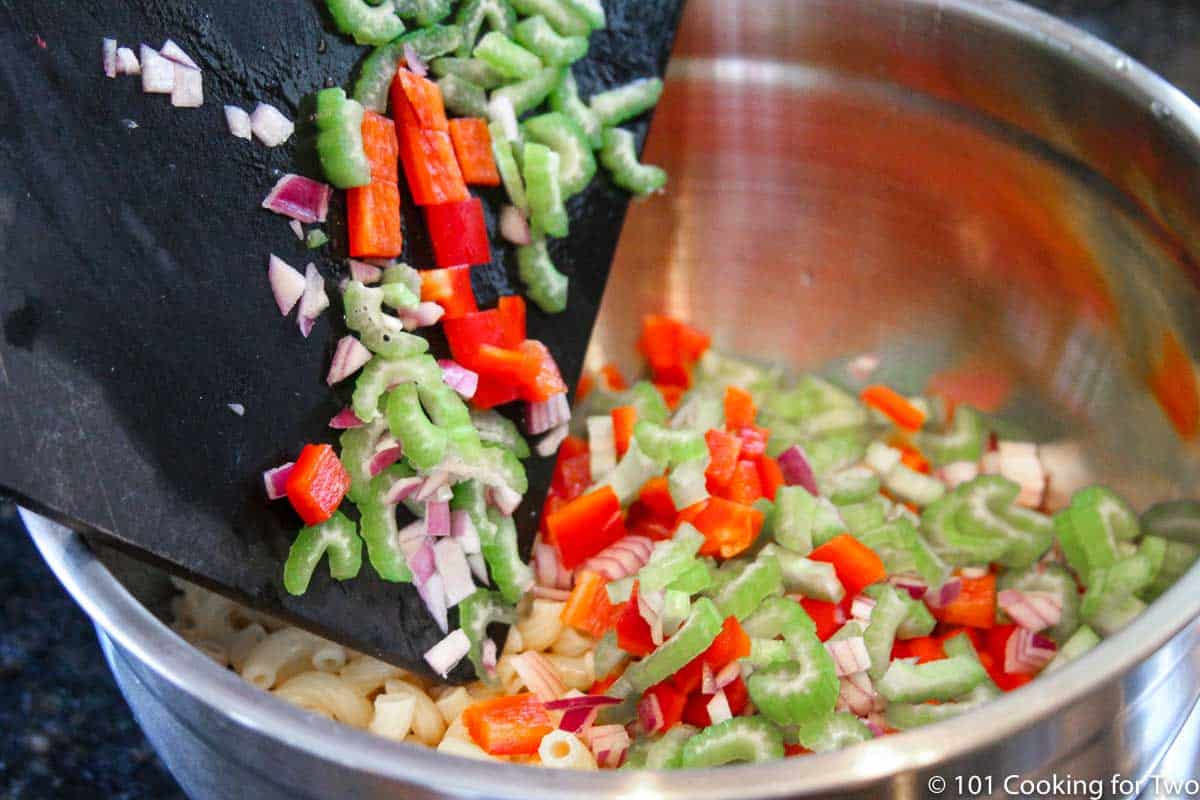adding chipped vegetables to cooked pasta