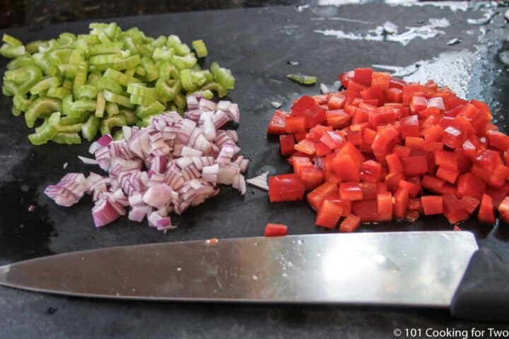 chopped onion with celery and red pepper on a black board