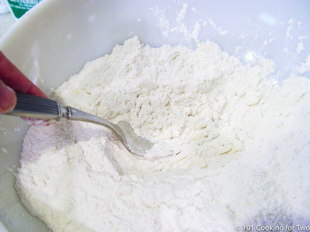 cutting butter into flour in a white bowl