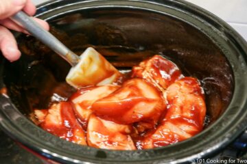 mixing chicken into the sauce in the crock pot