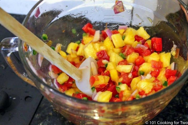 mixing salsa ingredients in a glass bowl