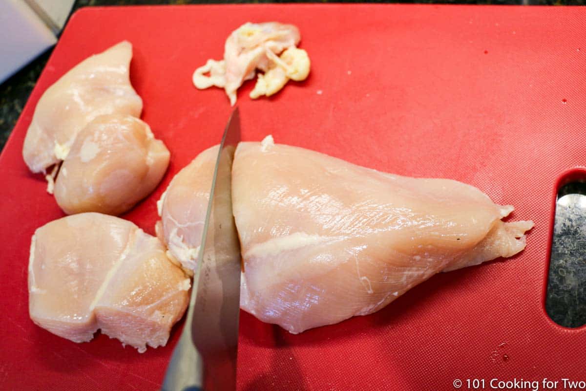 trimmed chicken breasts on a red board
