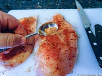 applying the seasoning to the chicken on a white board