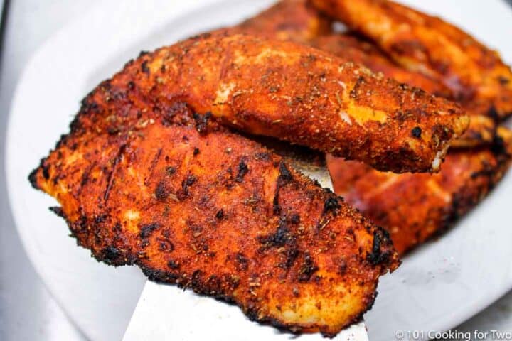 Grilled Blackened Tilapia from 101 Cooking for Two pile of blackened tilapia on a white plate.