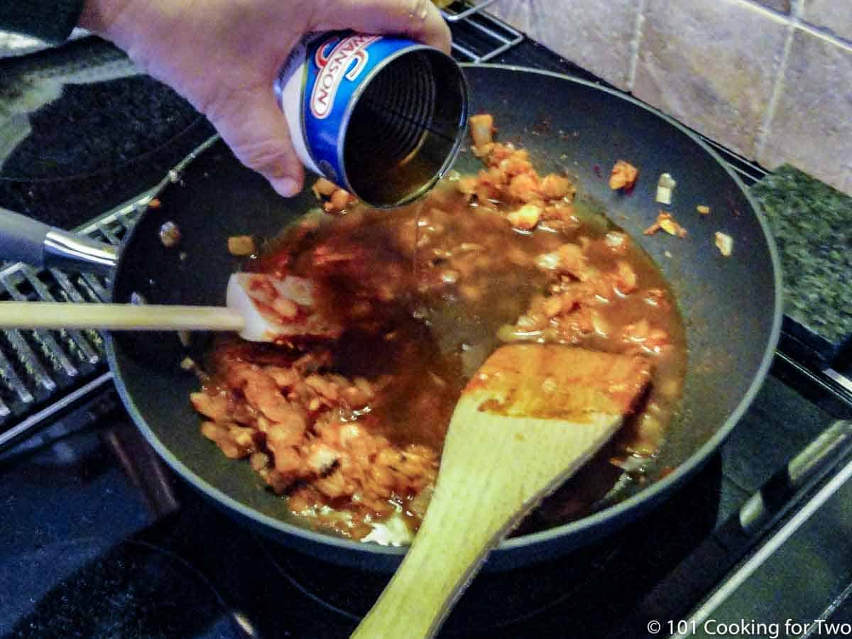 adding broth to frying pan with onion.