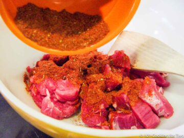 adding spices to bowl with cut up pork