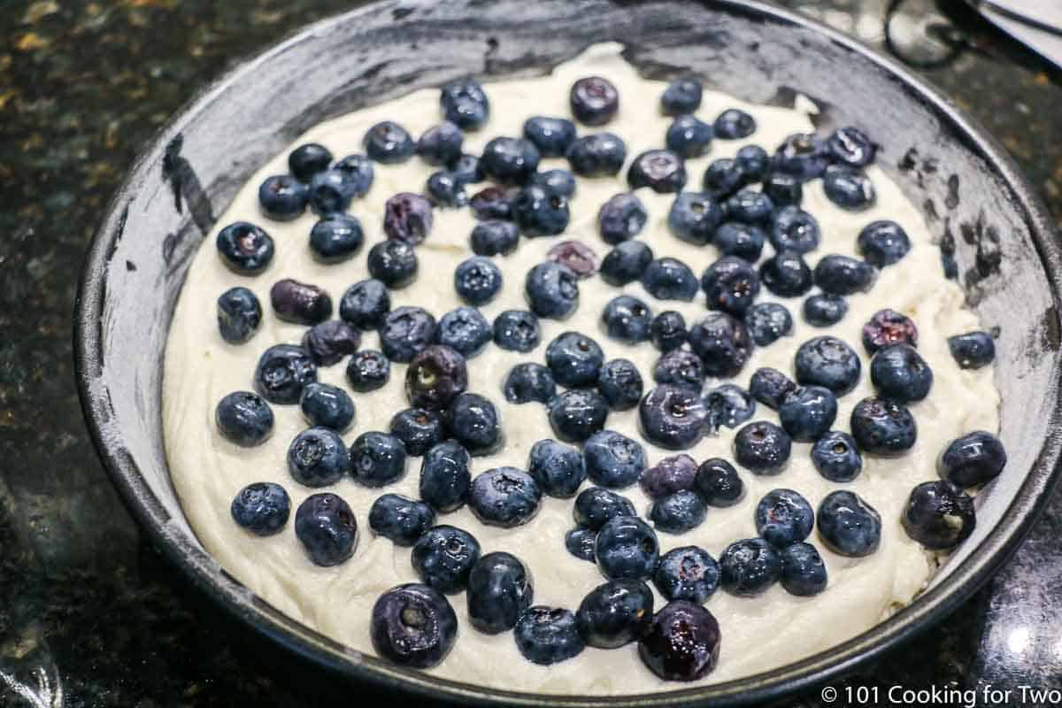 cake batter in pan topped with blueberries.