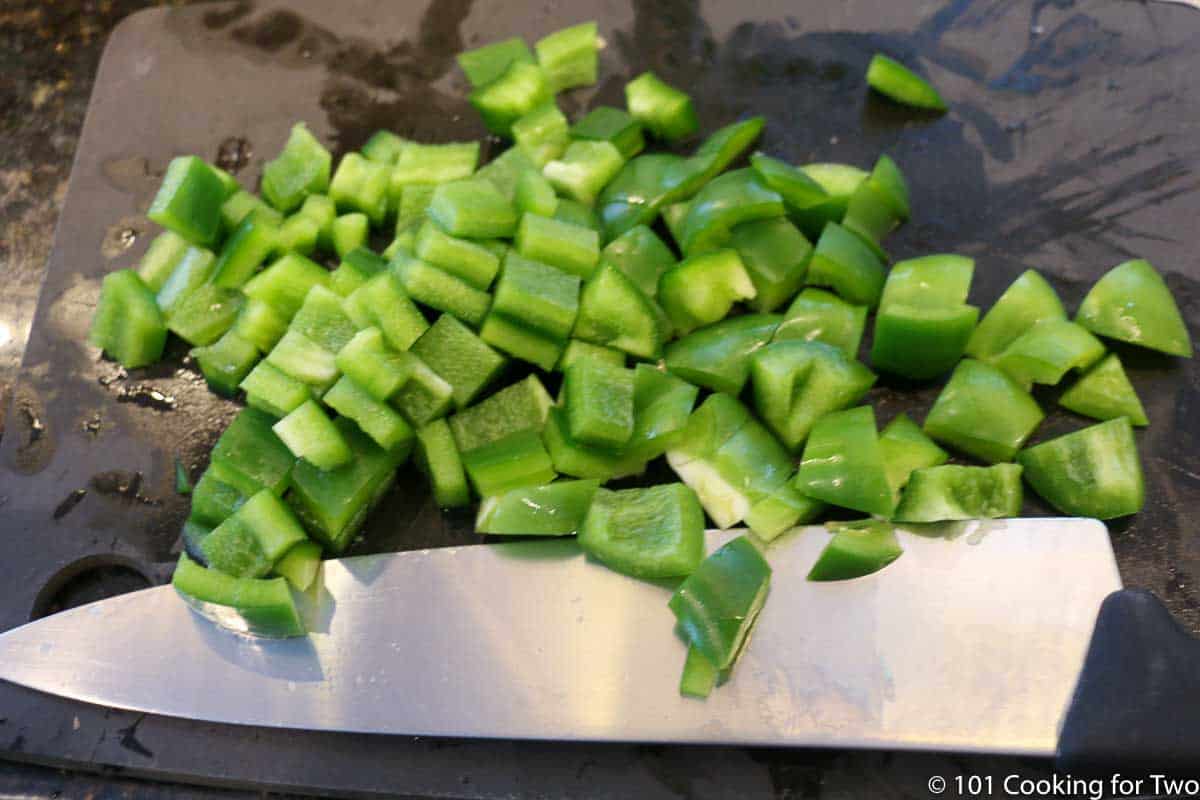 chopped green pepper on black board.