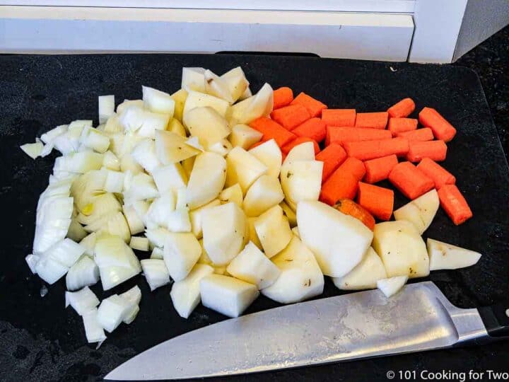 chopped onion with potatoes and carrots on black board