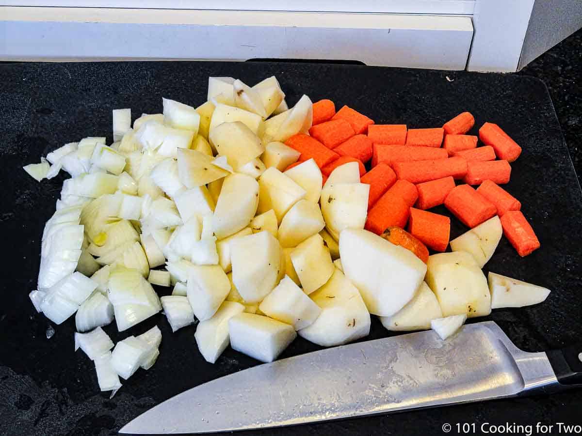 chopped onion with potatoes and carrots on black board.