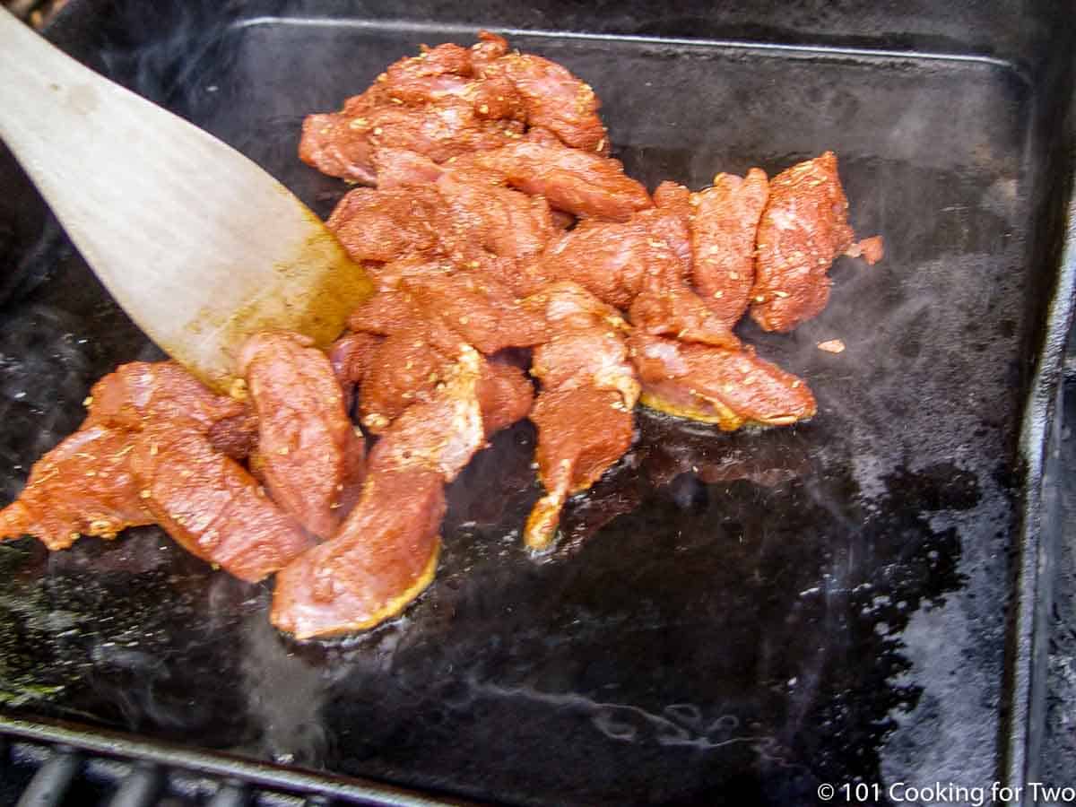 pork chunks cooking on the griddle.