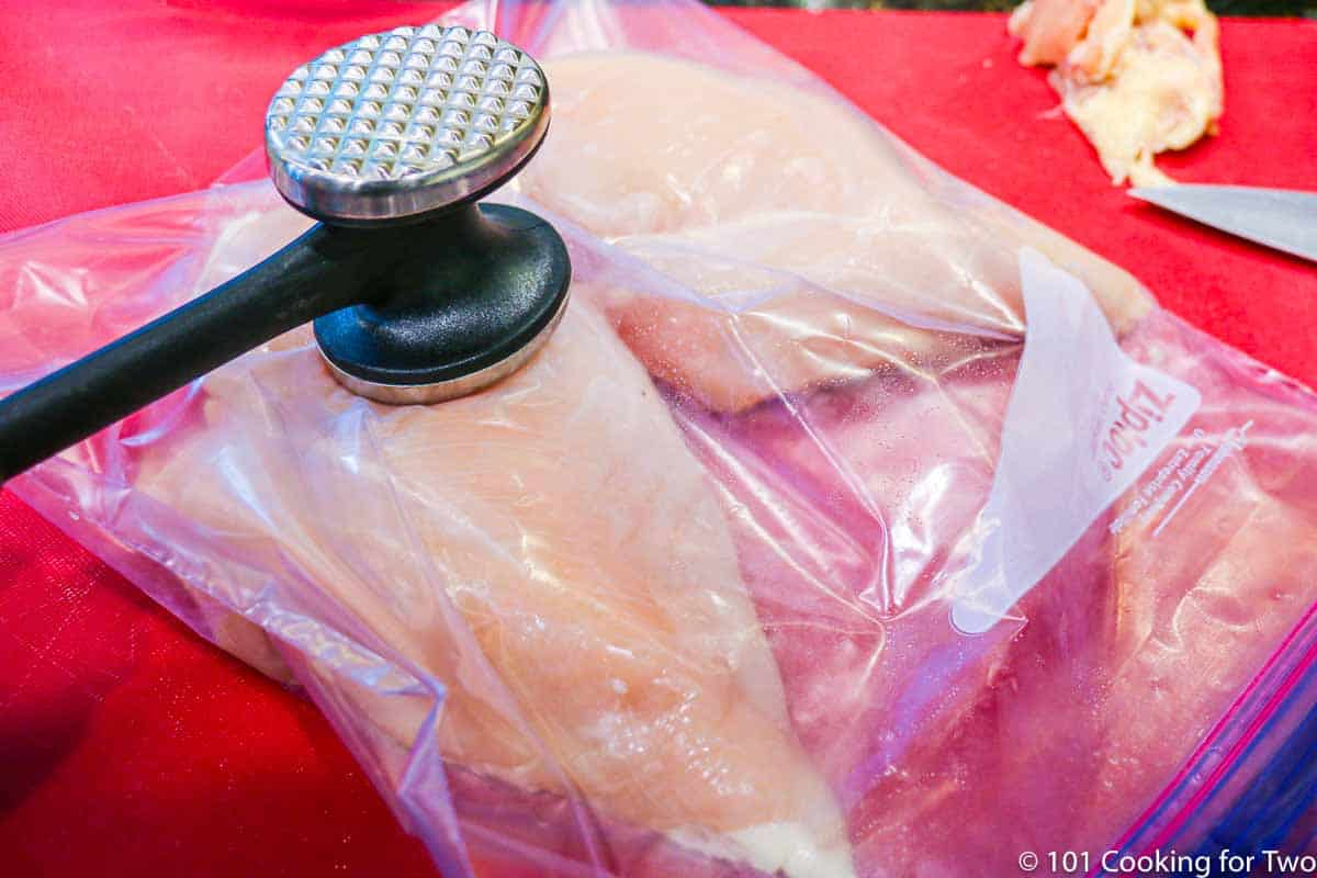 raw chicken breasts in bag being flattened.