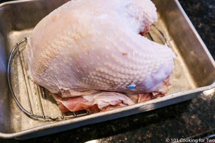 raw whole turkey breast on a rack.