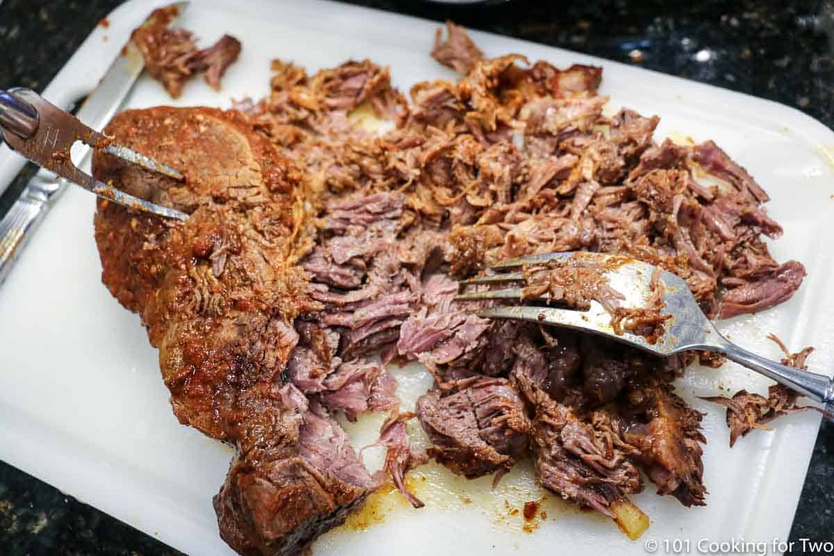 shredding beef on a white board.