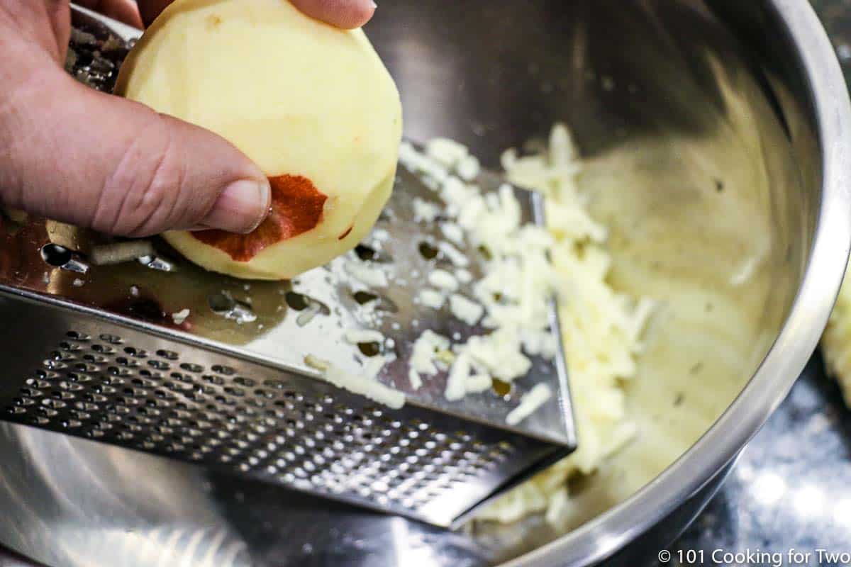shredding an apple into a metal bowl.