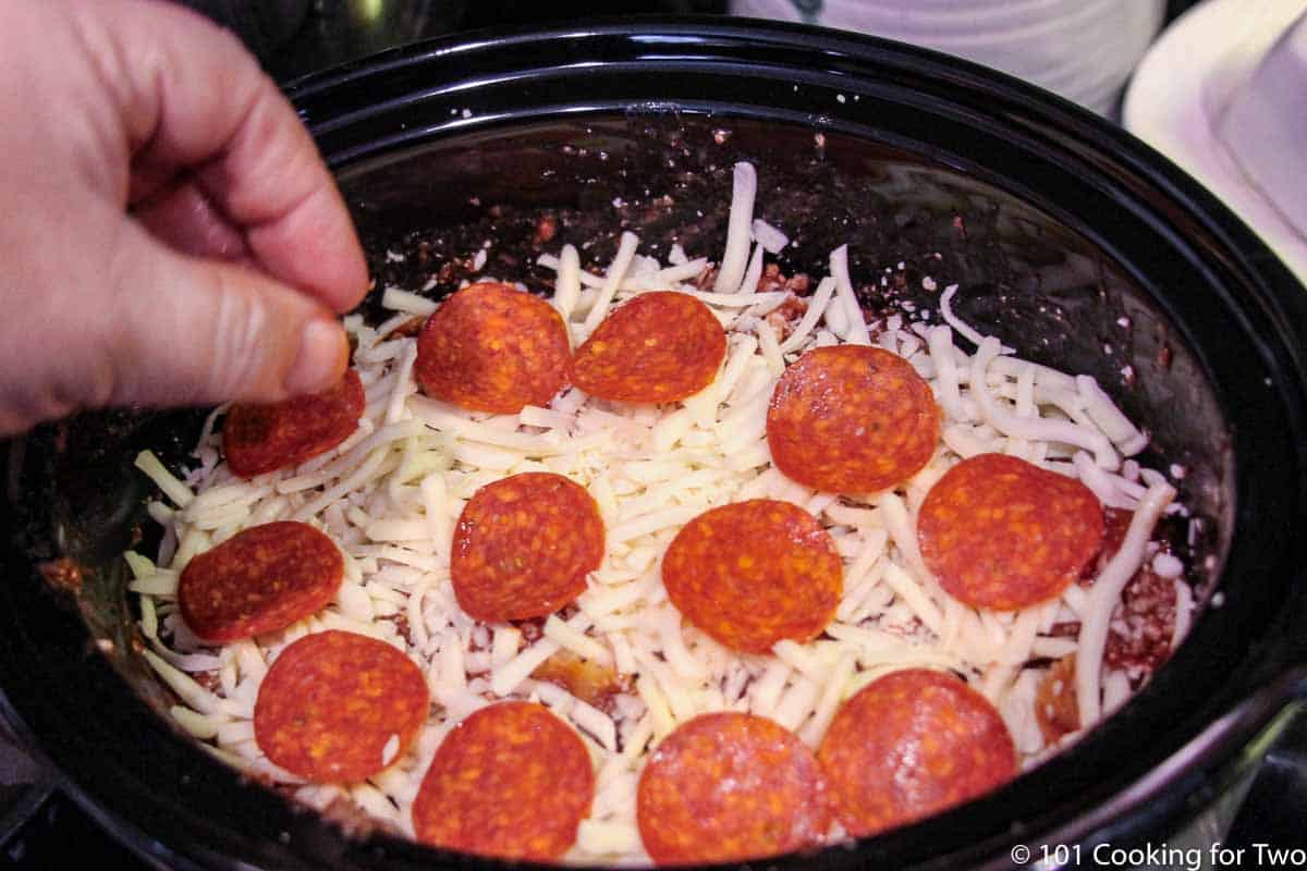 topping the pizza casserol with pepperoni.