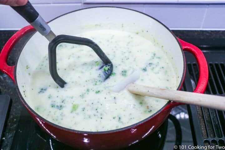 using a potato masher on the soup