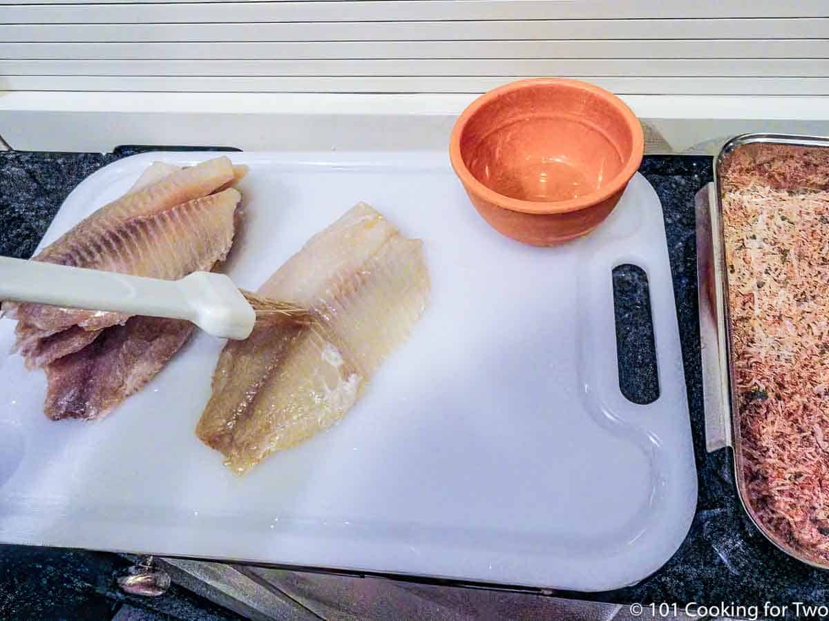 brushing raw tilapia with oil.