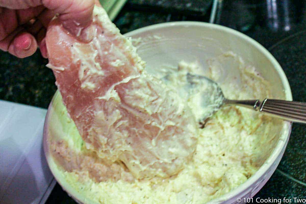 coating a chicken breast with mayo mixture.