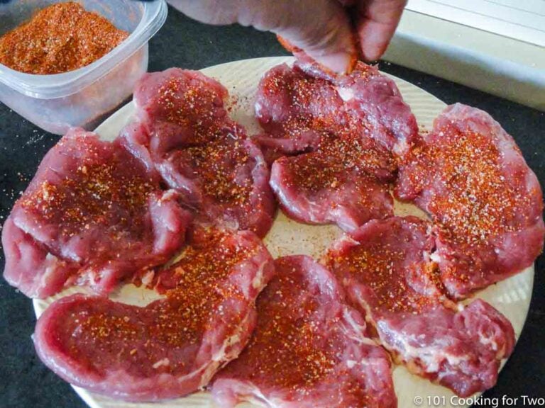 sprinkling seasoning on the pork slices