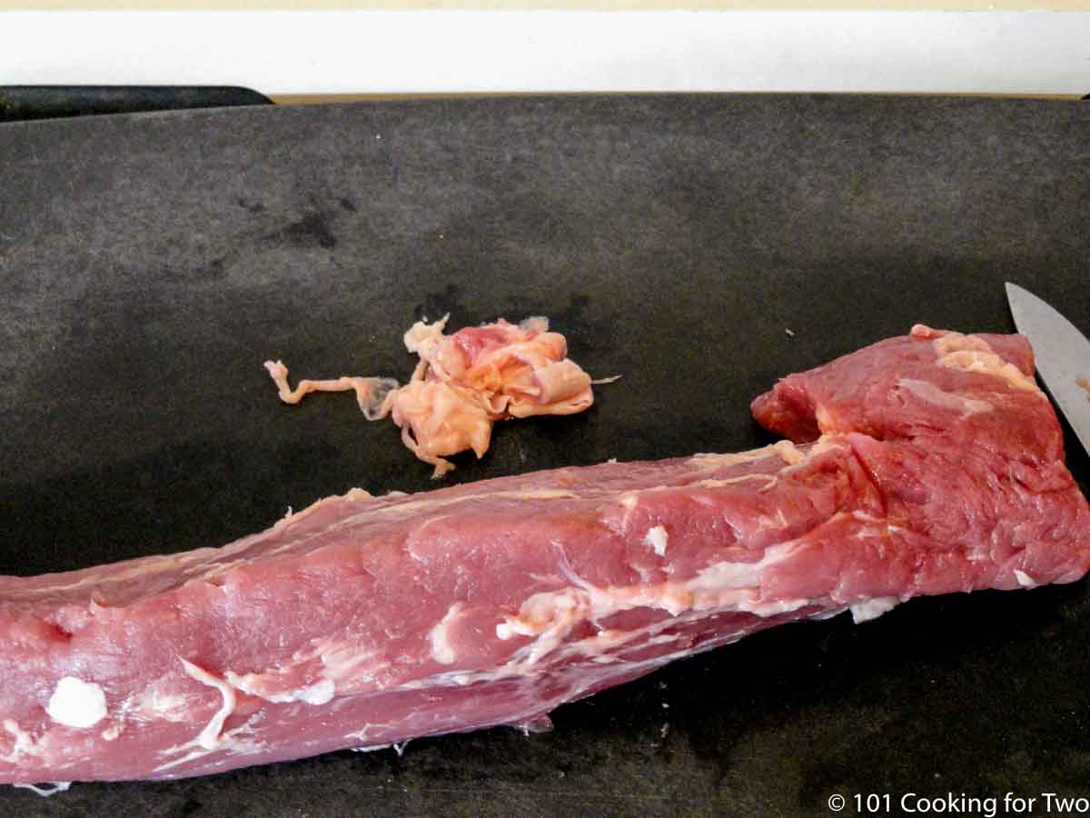 Trimmed pork tenderloin on a black board.