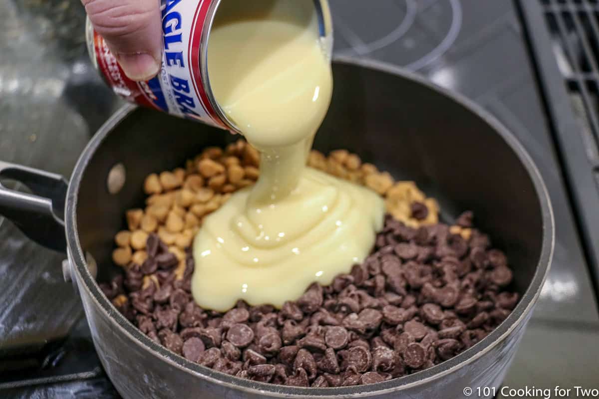 Pouring sweatened condensed milk to pan with chips.