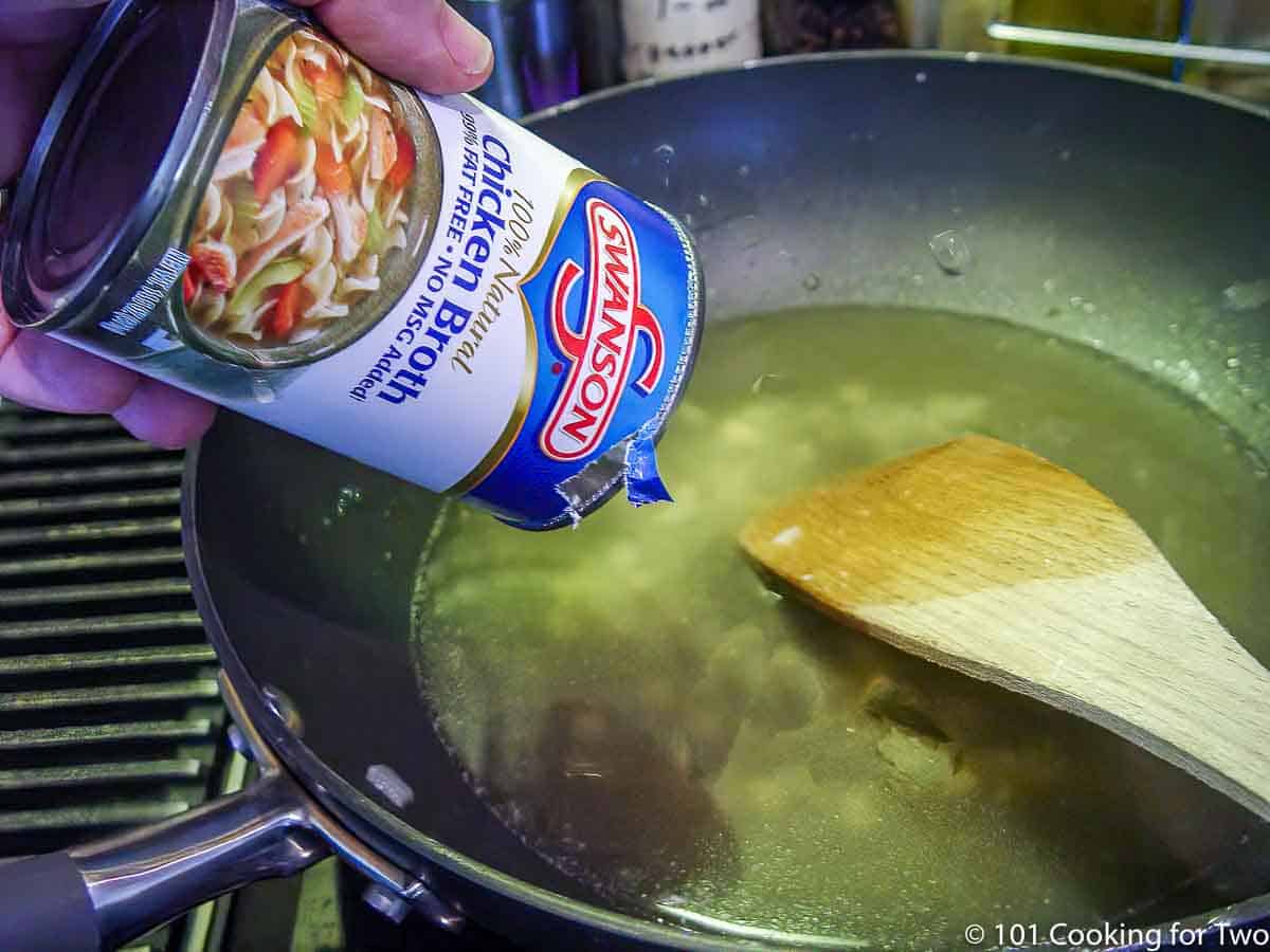 adding broth to a fry pan