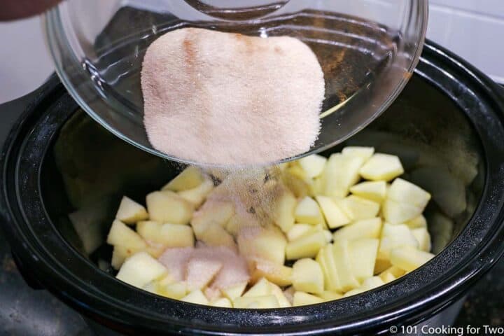 adding cinnamon sugar mixture to apples in crockpot