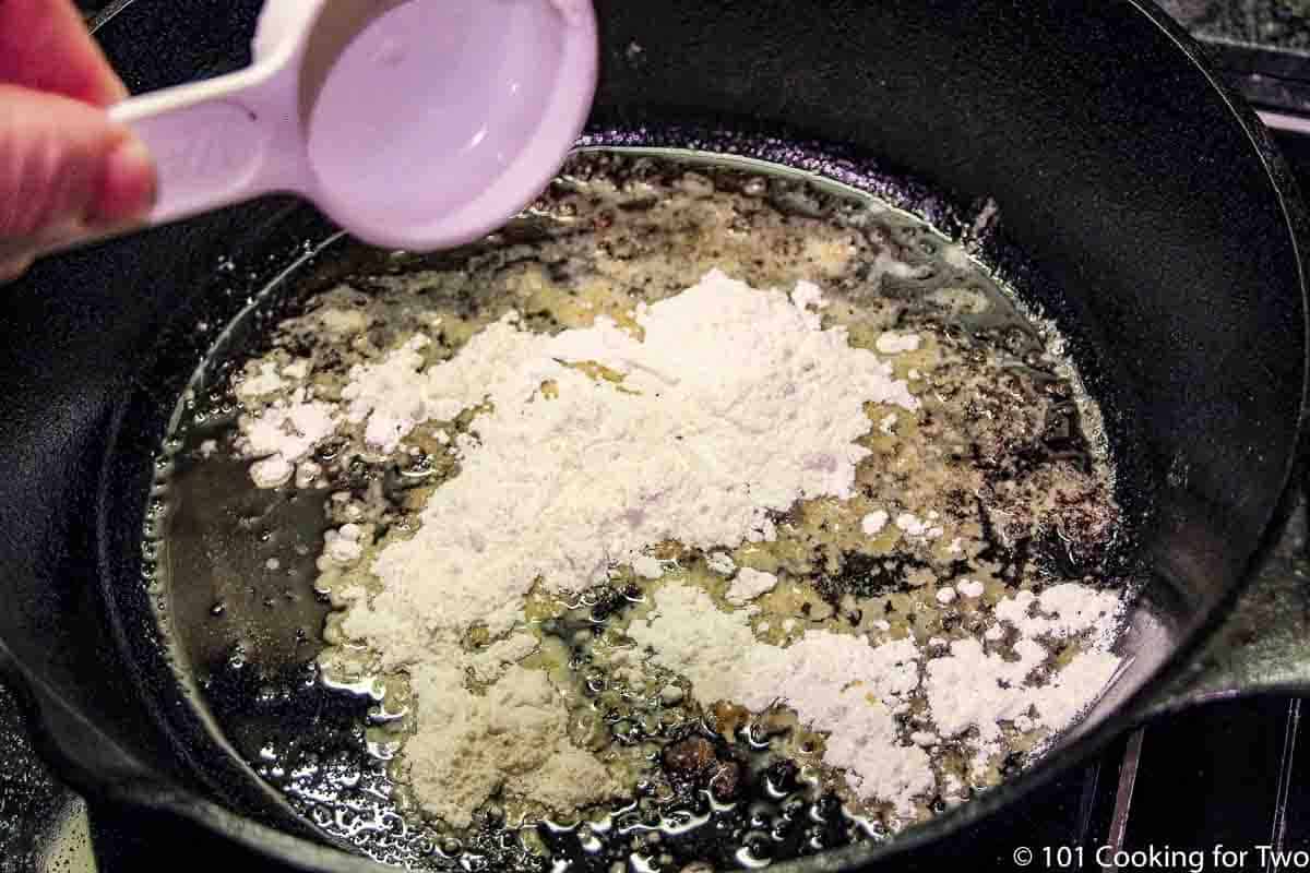 https://www.101cookingfortwo.com/wp-content/uploads/2021/11/adding-flour-to-fat-in-black-pan.jpg