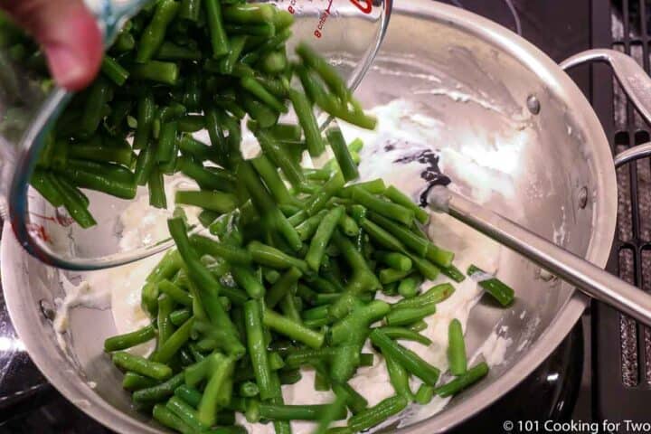 adding green beans to sauce