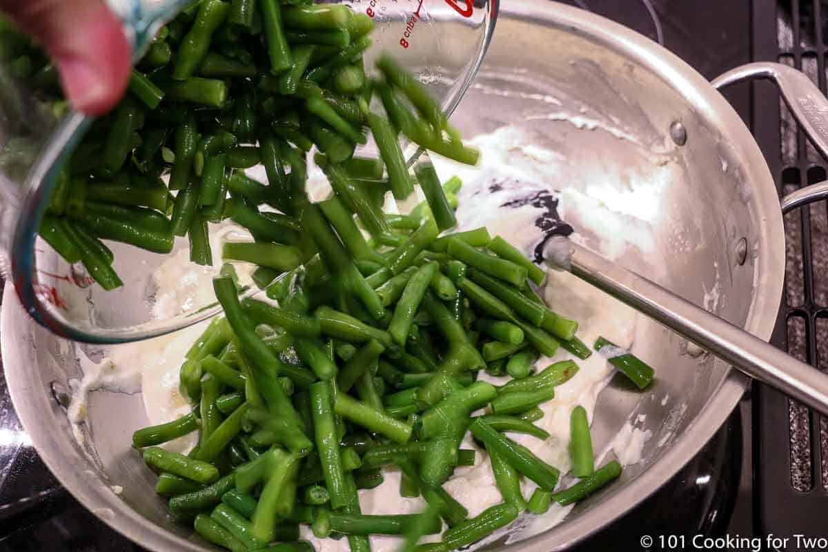 adding green beans to sauce.