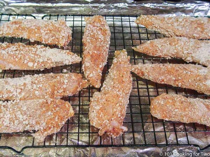 coated raw chicken tenders on a rack_
